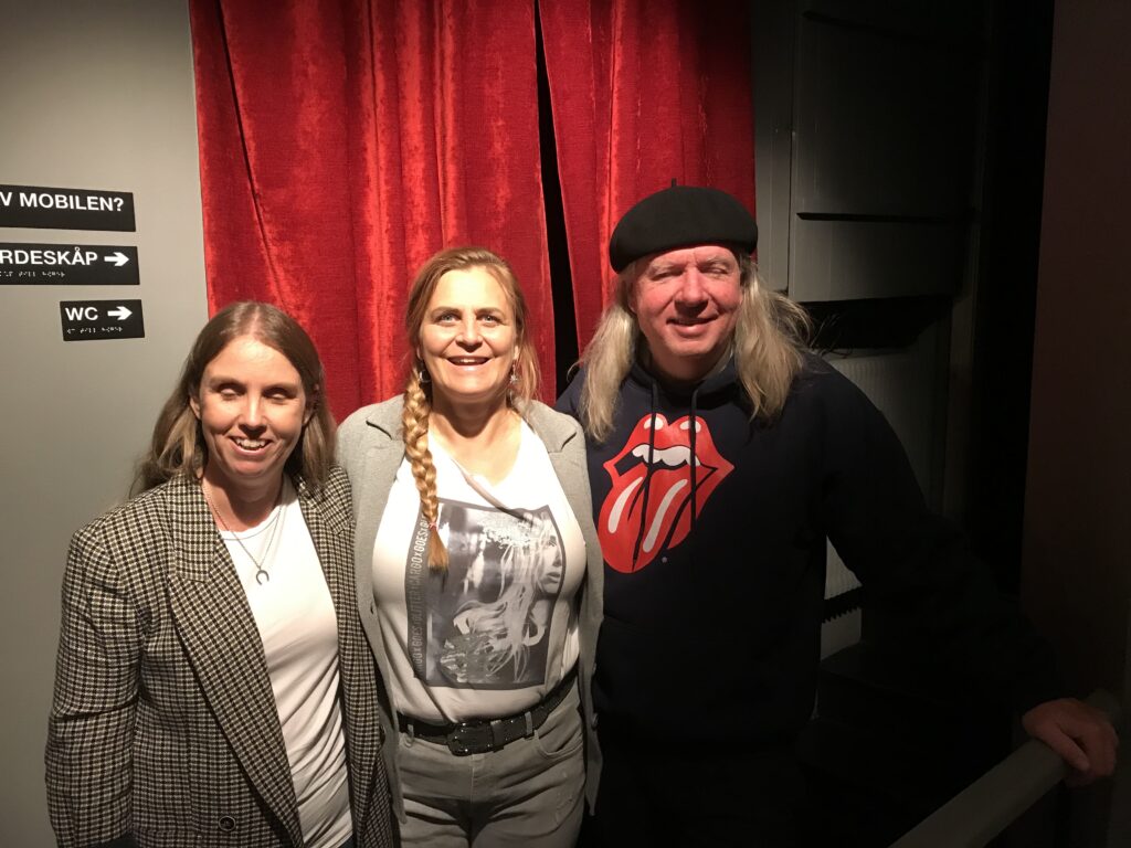 Anna, Tina och Ulf i studion. anna har långt blont hår, grårutig kavaj, vit topp och halsband med en hästsko. Tina har blont hår i lång fläta, grå tröja, gråa byxor, vit topp. Ulf har långt grått hår, svart basker, svart tröja och byor. Bakom syns ett rött drapperi.